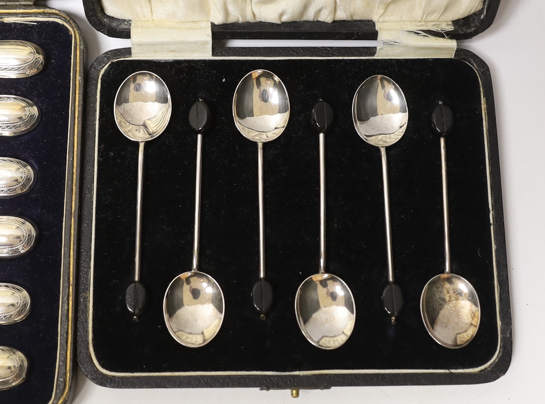 A cased set of six 1930's silver bean end coffee spoons, Birmingham, 1931 and a cased set of six handled tea knives.